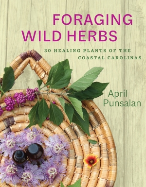 Muted green wooded plank background, with purple herbs placed in a brown basket. Purple title top right; green author name middle right.